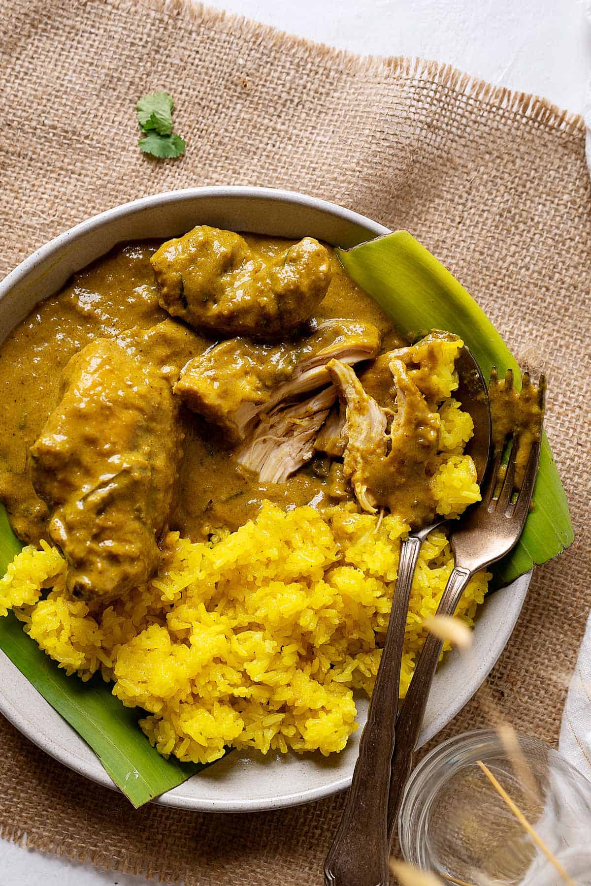 Half eaten slow cooker chicken rendang in a plate with some turmeric glutinous rice