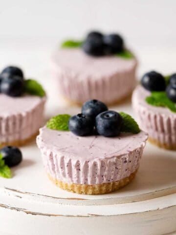 mini blueberry cheesecakes on a cake stand.