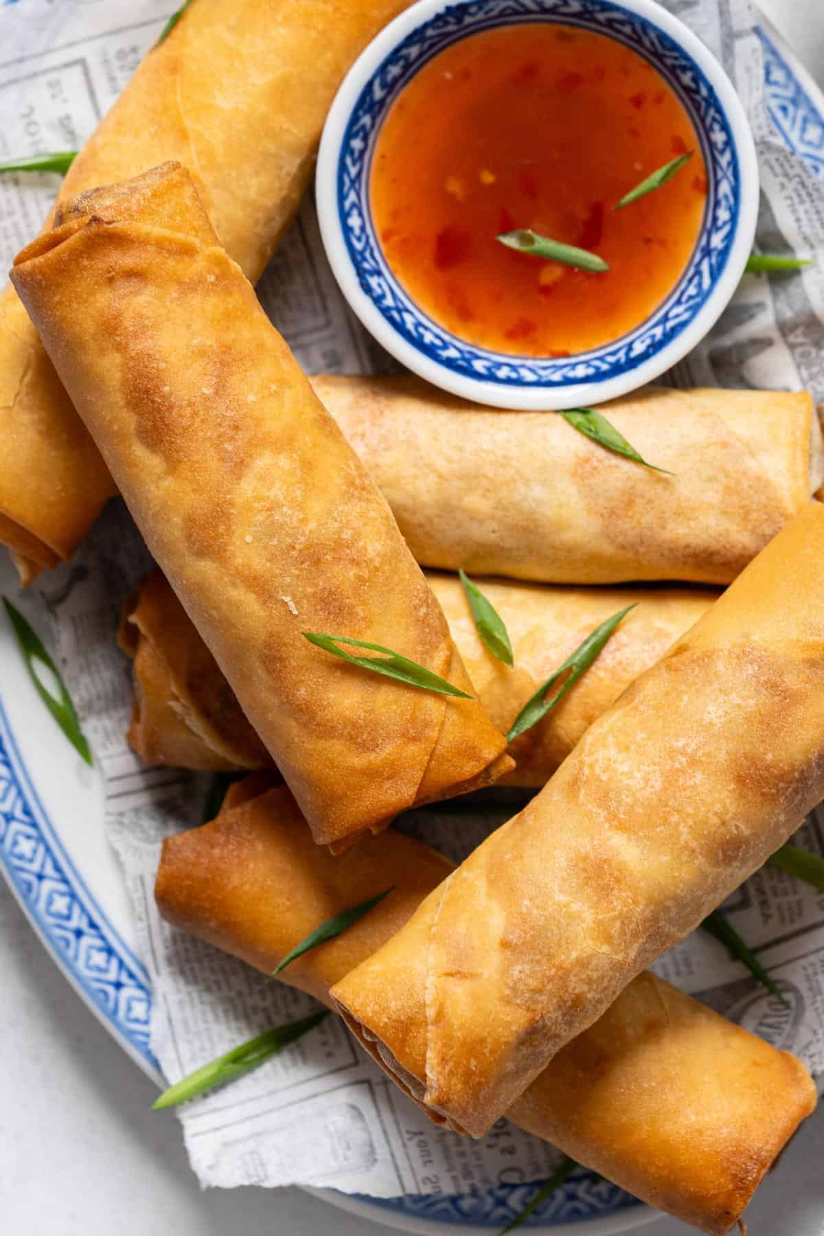 Spring rolls on a plate with dipping sauce.