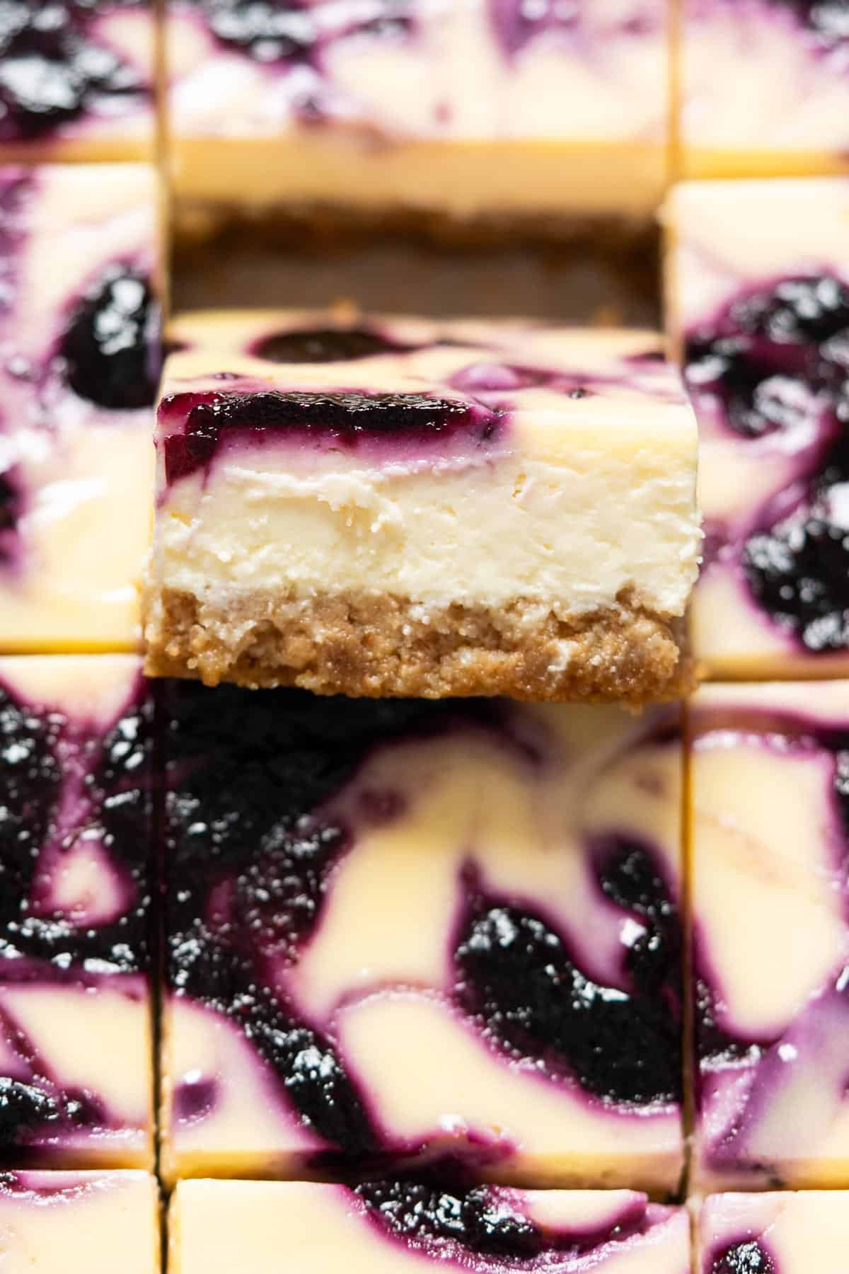 Close up of a piece of blueberry cheesecake bars.