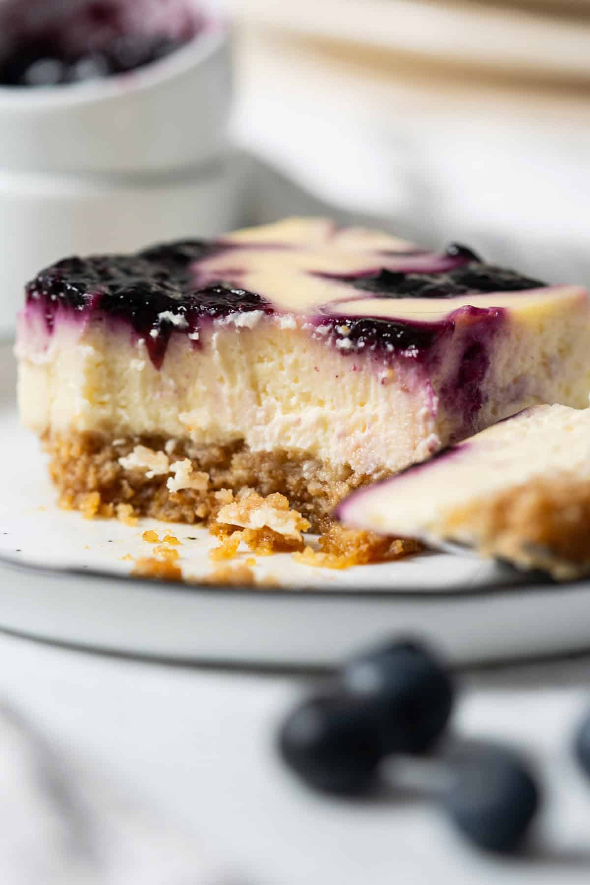 Showing the creamy texture of a half-eaten slice of blueberry cheesecake bar.