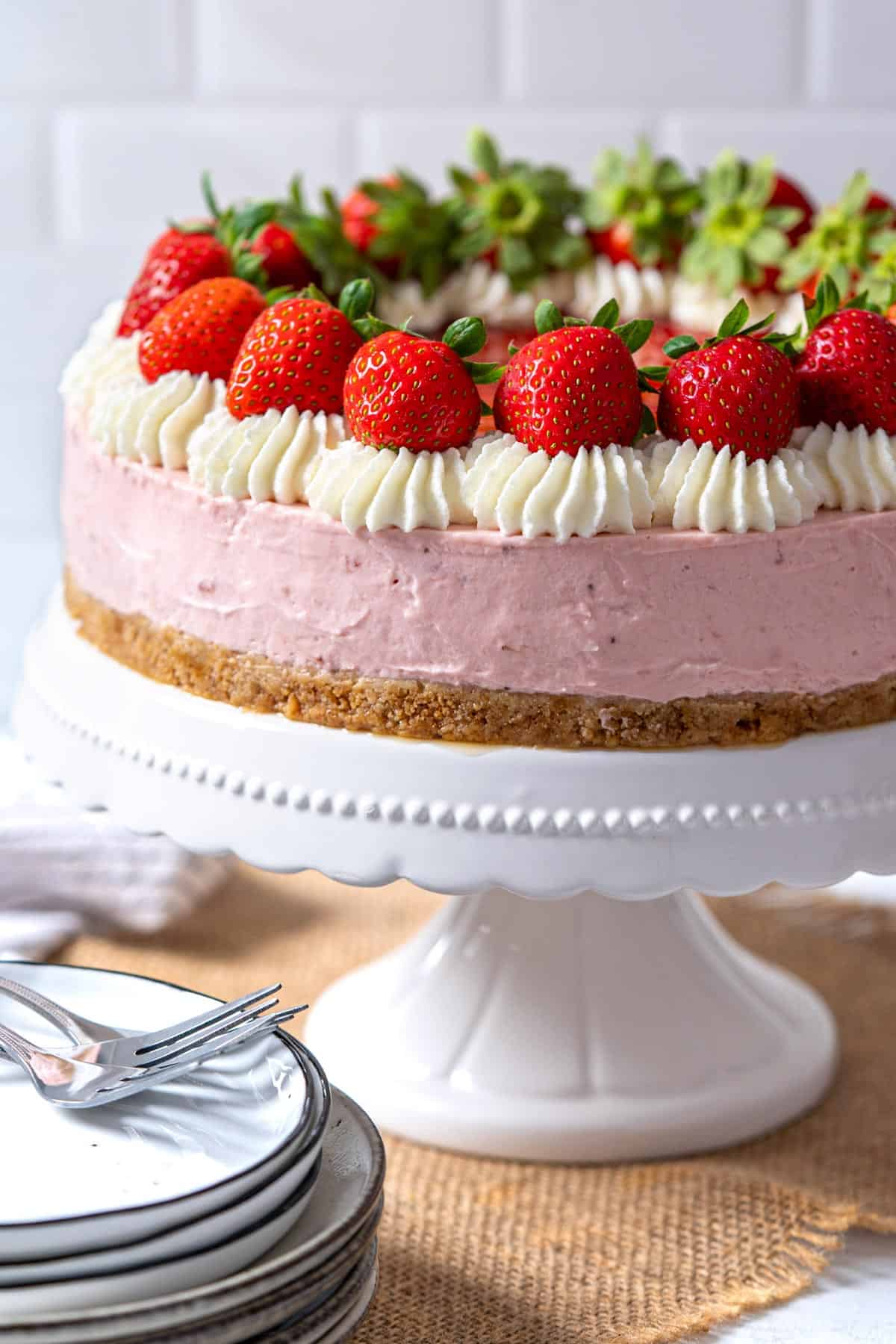 Creamy strawberry cheesecake on a cake stand.