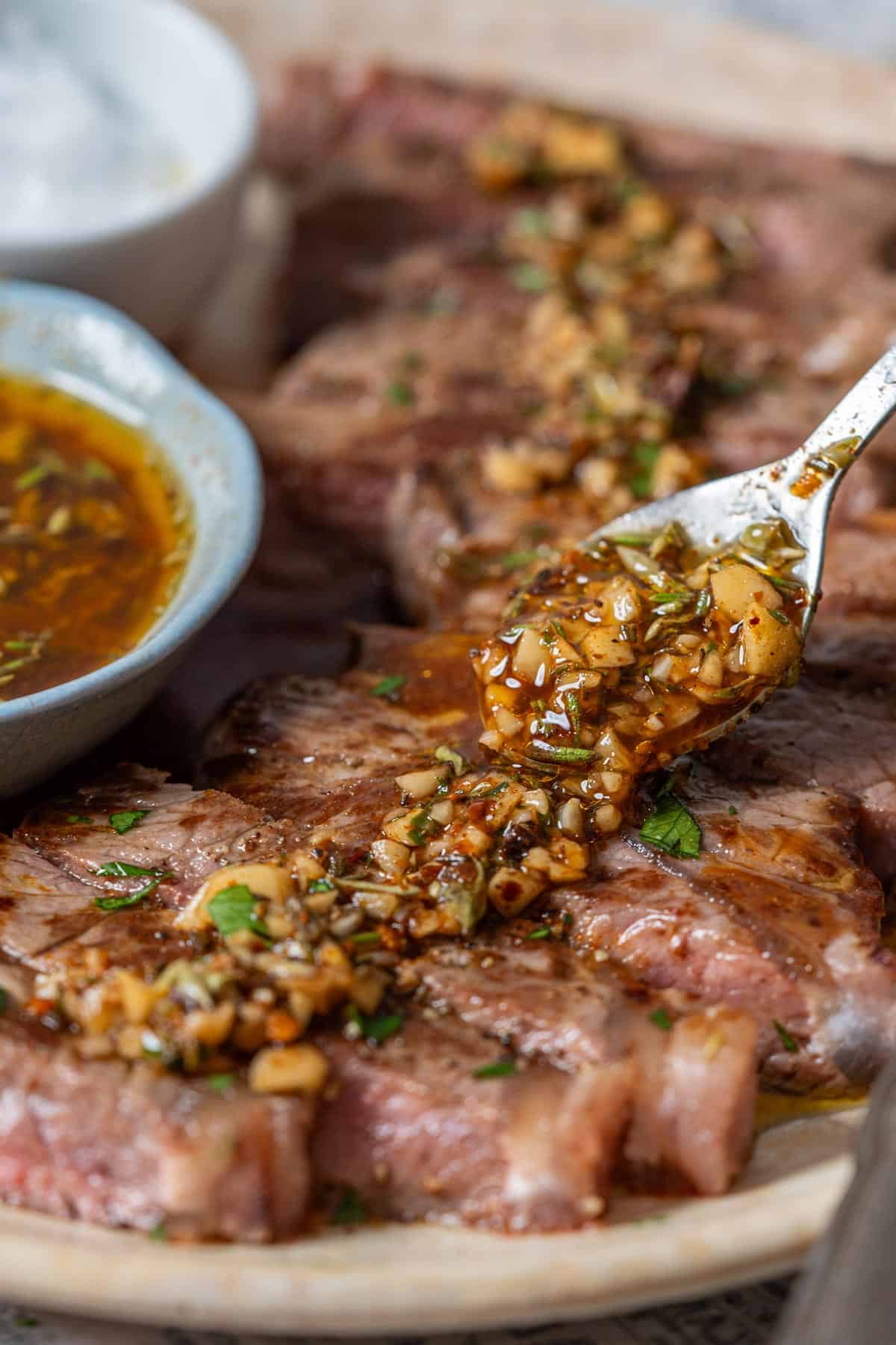 Spooning some chimichurri on grilled meat.