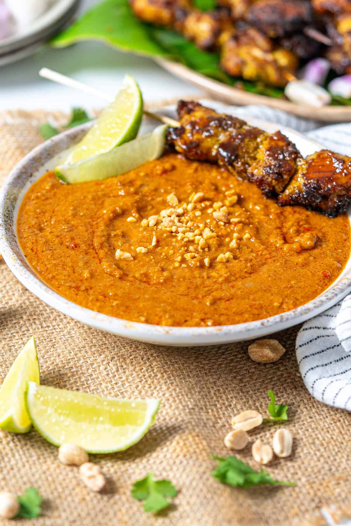 A bowl of Malaysian satay sauce with chicken satay.