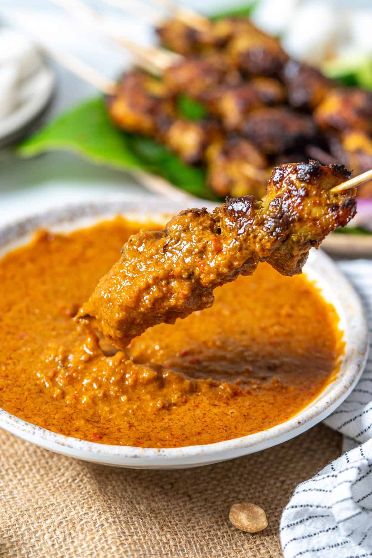 Dipping chicken satay in satay sauce.