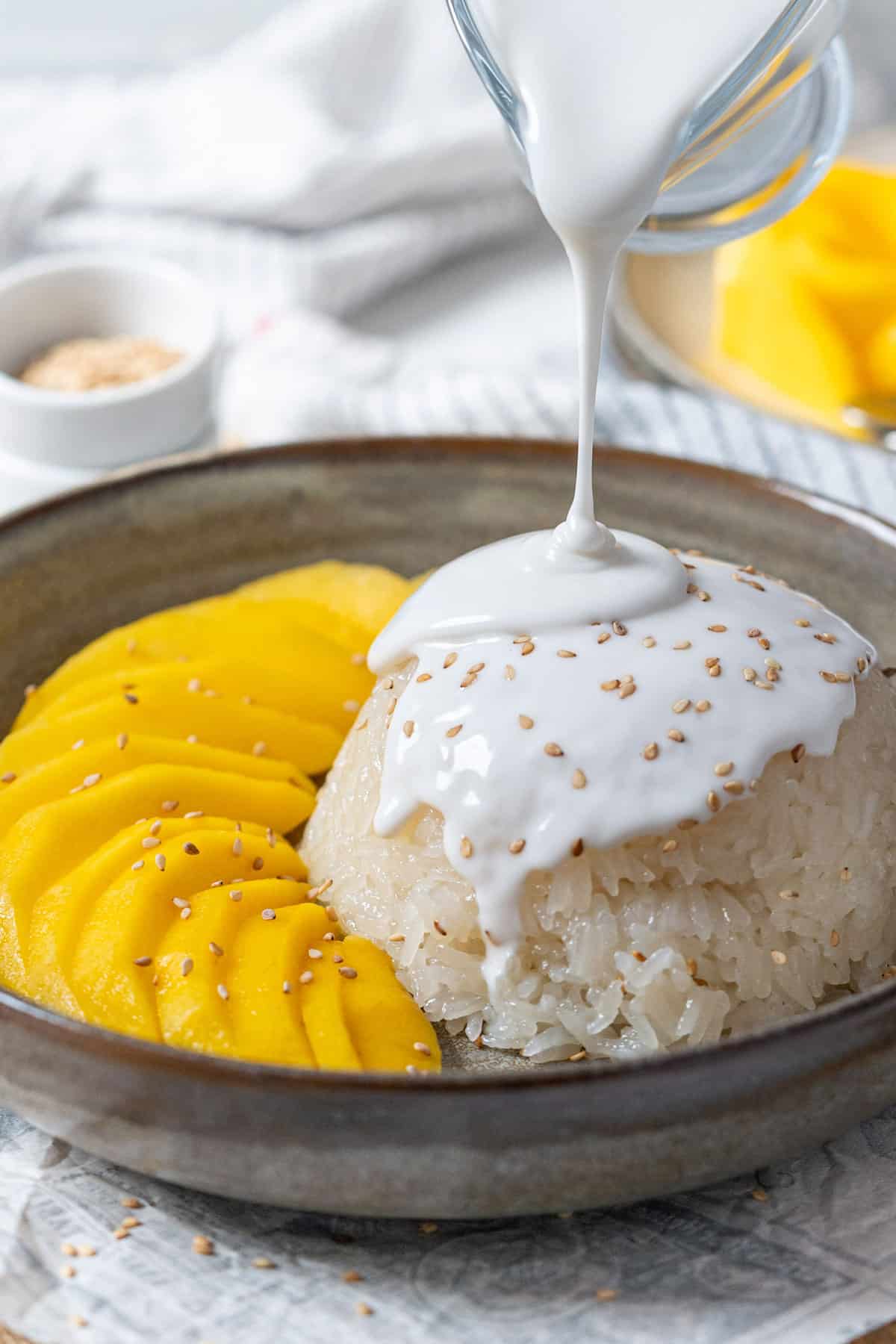 Pouring coconut sauce on sticky rice.