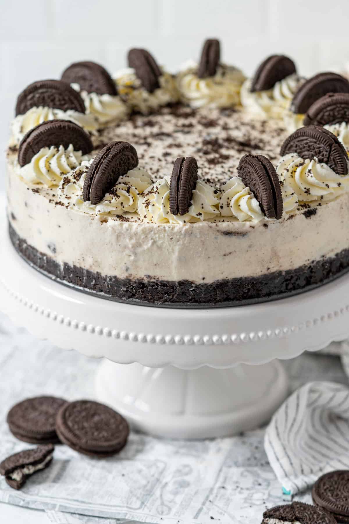 A whole no-bake Oreo cheesecake on a cake stand.