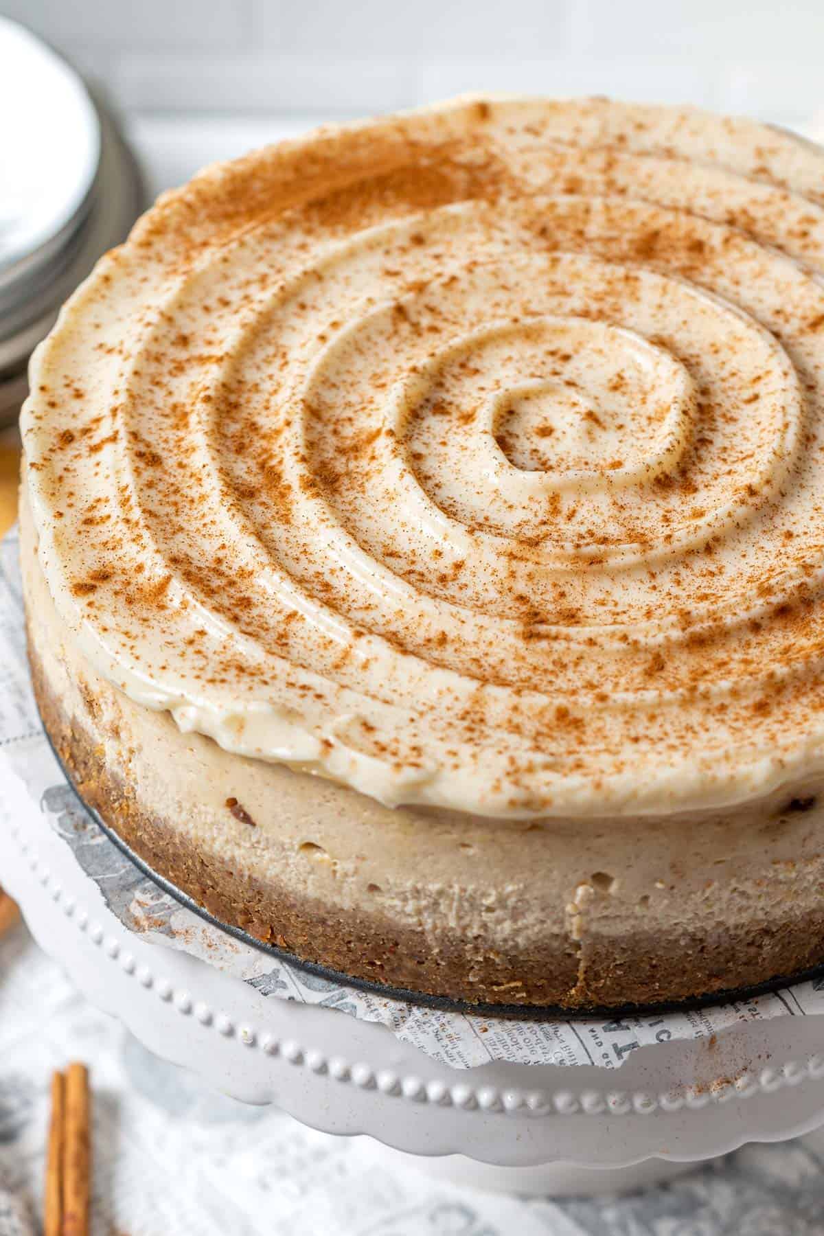 A whole cinnamon cheesecake on a cake stand.